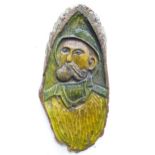 A carved wooden plaque depicting a portrait of a fisherman smoking a pipe. Ascribed in German verso.