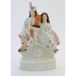 A Staffordshire flat back figural group depicting a Scottish highland couple with clock detail