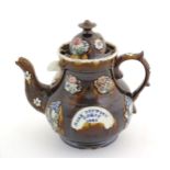 A Victorian treacle glazed bargeware teapot with applied floral decoration and a banner for Mary