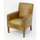 A late 20thC tan leather armchair with studwork detailing and standing on tapering legs. 26" wide