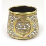An early 20thC Middle Eastern brass pot of tapered form with engraved detail and inlaid white