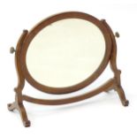 An early / mid 19thC mahogany toilet mirror with shaped supports flanking an oval mirror to the