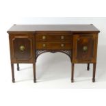 An early 20thC walnut sideboard with an inverted breakfront above two long drawers flanked by two