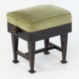 An early 20thC ebonised Arts and Crafts style piano stool with an upholstered top that rises using a