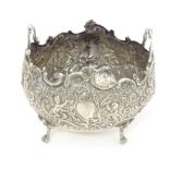 A Continental white metal twin handled bowl with embossed floral, C scroll and cherub decoration,