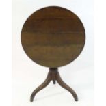 A late Georgian oak tripod table with a circular planked top above a turned pedestal base and
