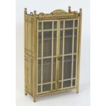 A mid 20thC wall hanging cabinet surmounted by four turned finials and a bentwood pediment, having