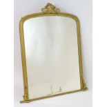 A Victorian gilt painted mirror of arched form surmounted by carved, pierced floral decoration