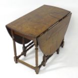 A 19thC oak drop flap table with rounded edges and leaves above eight turned legs united by a box