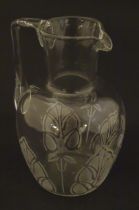 A glass water jug with foliate detail Approx 7" high Please Note - we do not make reference to the