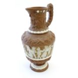 A large Continental pottery jug with moulded decoration and rams head handle. The body decorated