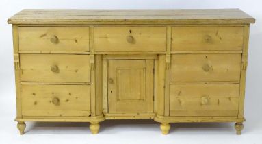 A Victorian pine dresser base with a moulded top above seven short drawers and a cupboard to the