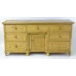 A Victorian pine dresser base with a moulded top above seven short drawers and a cupboard to the