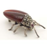 A silver and white metal brooch formed as a beetle, with red stone eyes, marcasite detail and garnet