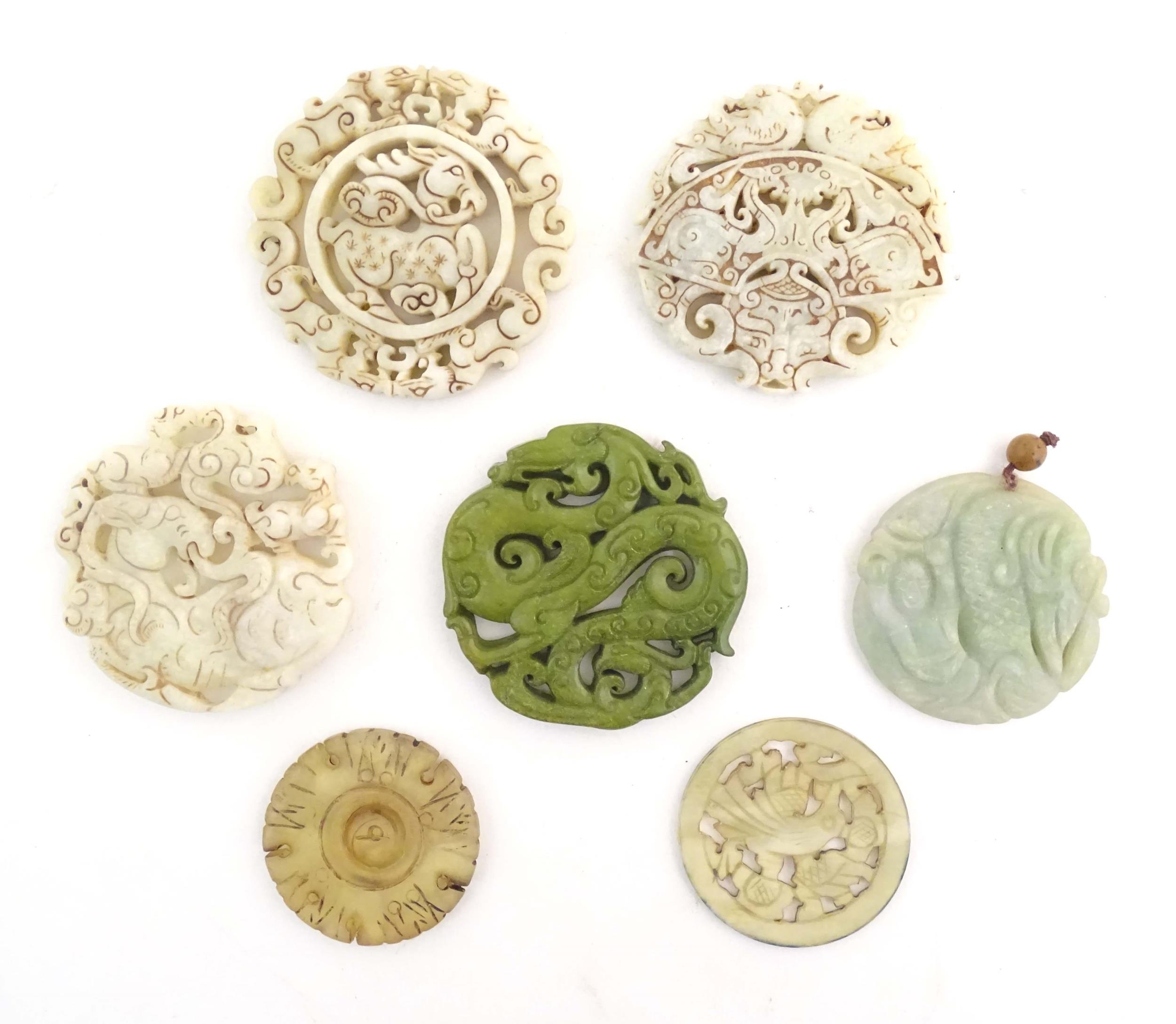 Seven assorted carved Oriental roundels / pendants, detail to include dragons, birds, stylised rams,