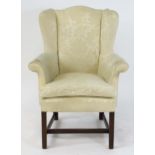 An early 20thC wingback armchair raised on chamfered mahogany legs united by a H-stretcher. 31" wide