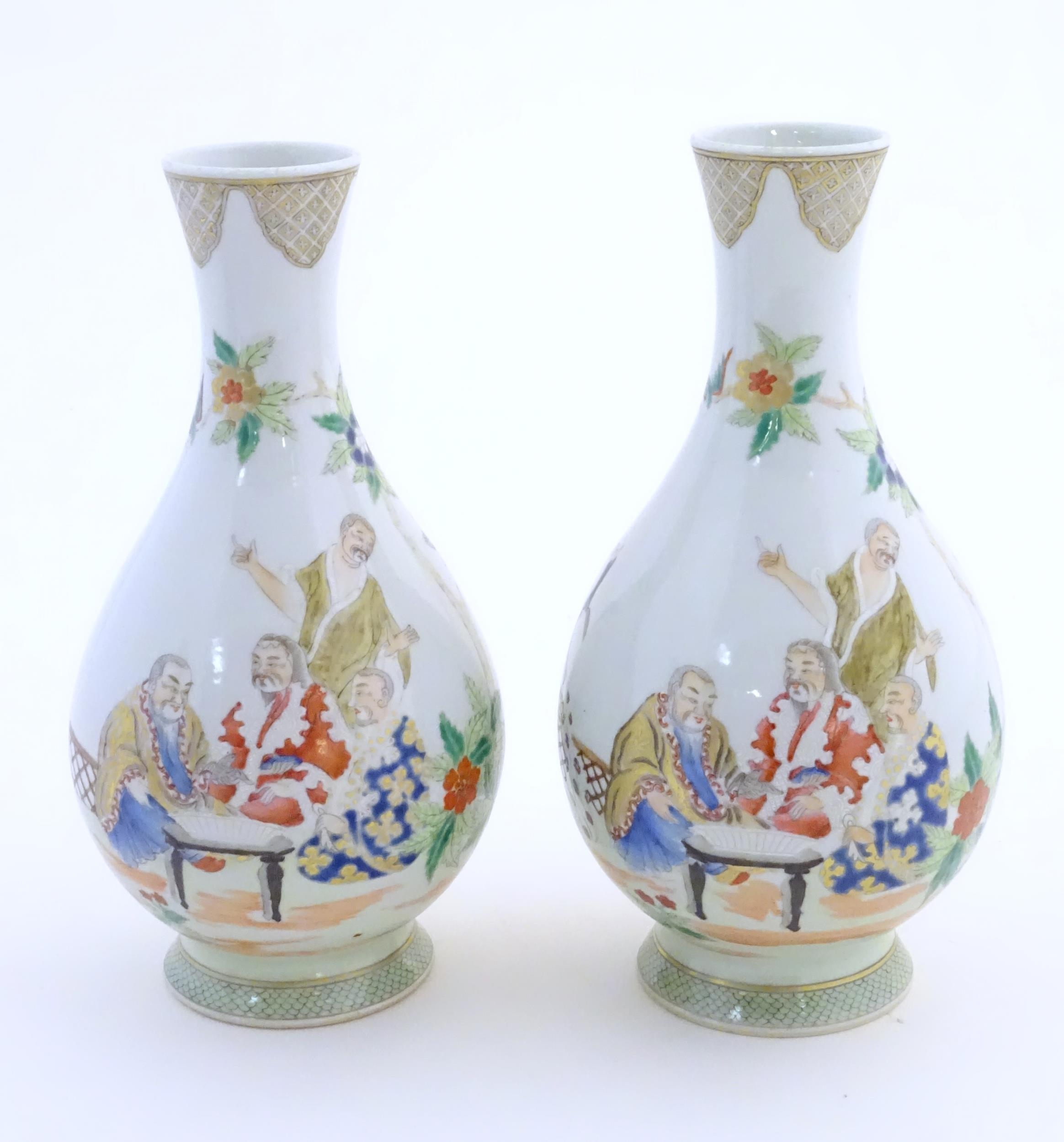 A pair of Chinese famille rose bottle vases decorated with seated figures on a garden terrace,