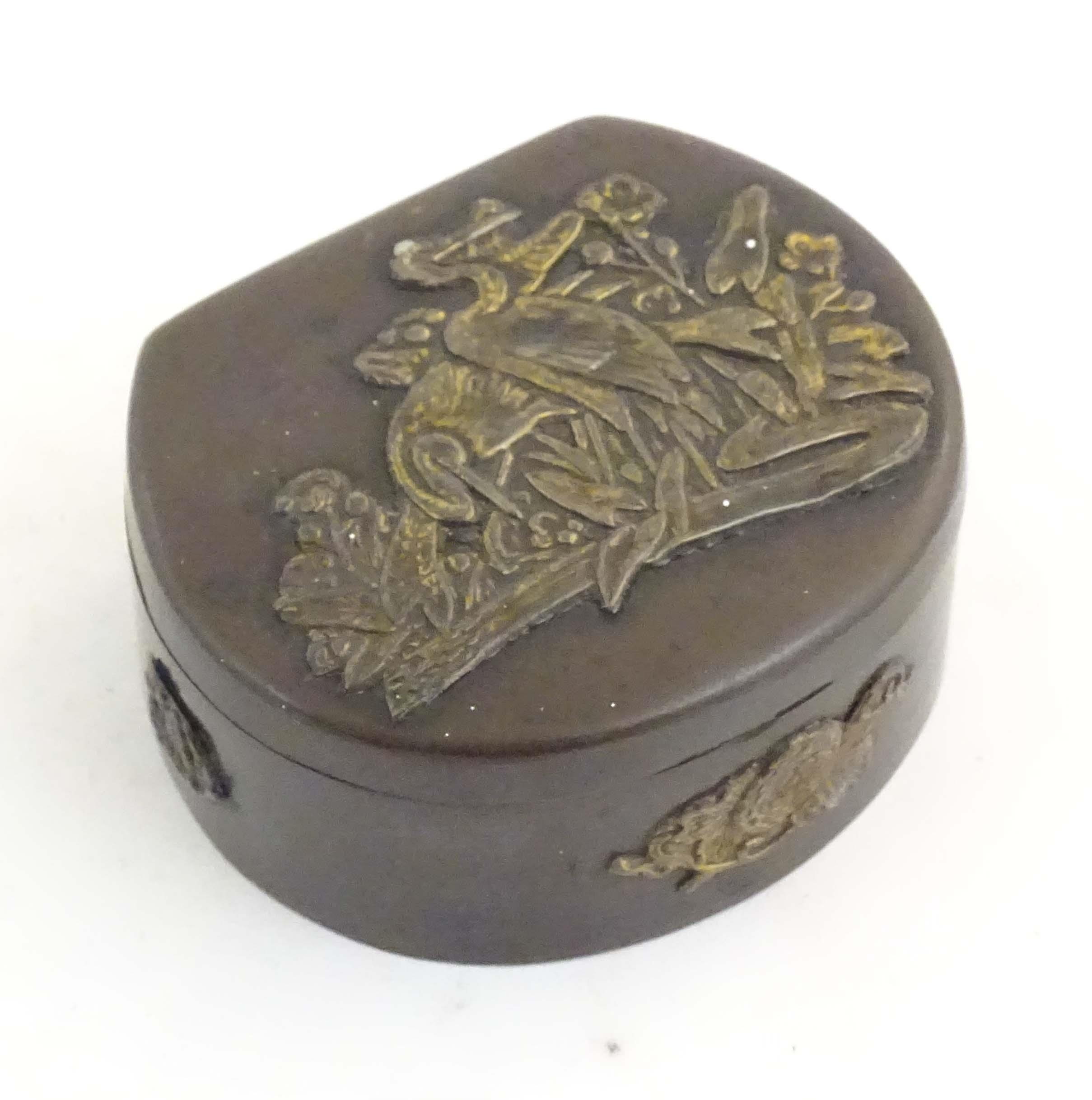 A Japanese lacquered brass stud box with a hinged lid, decorated with applied crane bird and