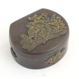 A Japanese lacquered brass stud box with a hinged lid, decorated with applied crane bird and