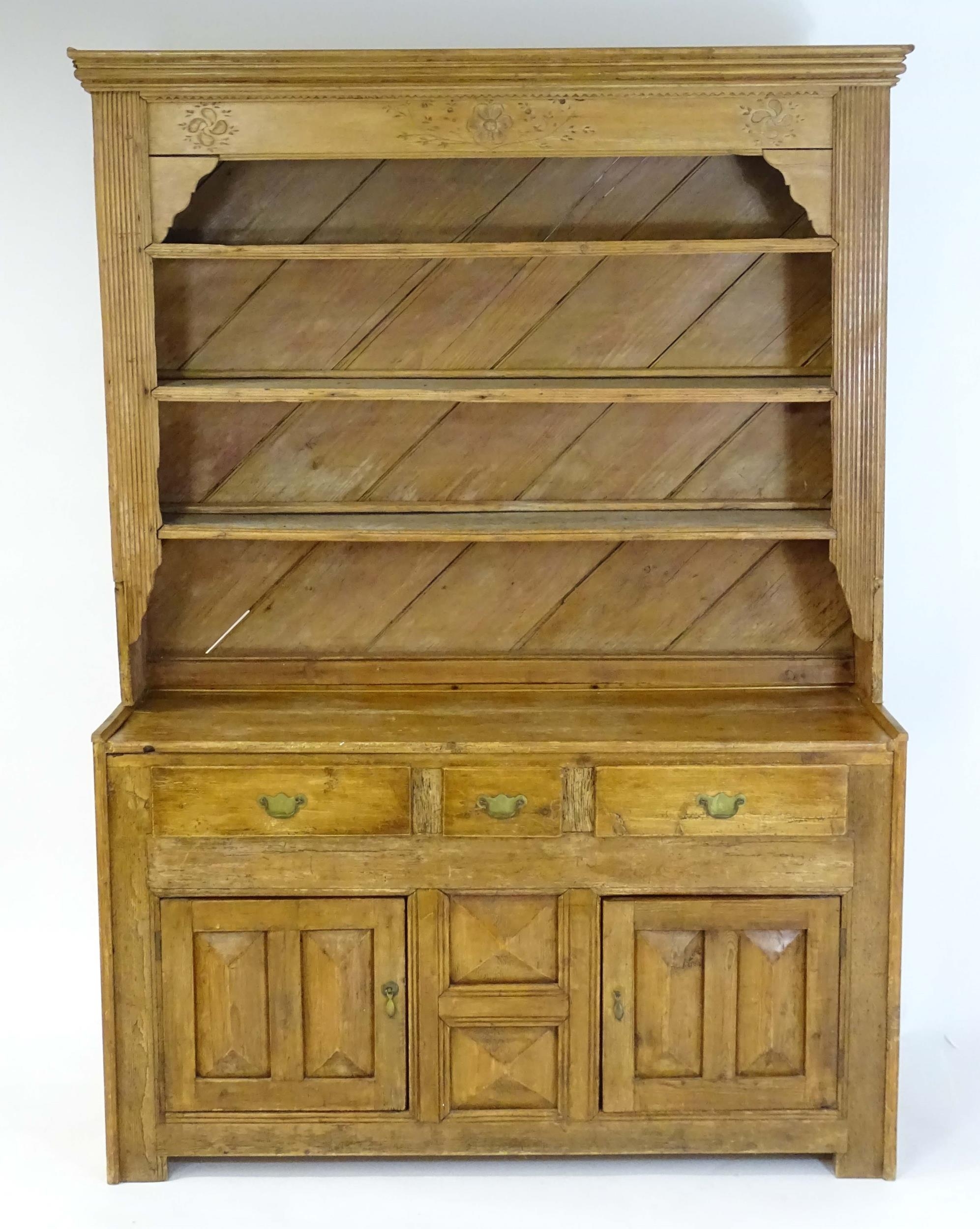 A 20thC pine dresser with a moulded cornice above floral carving flanked by reeded pilaster