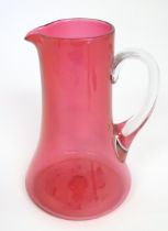 A cranberry glass jug with clear glass loop handle. 10" high Please Note - we do not make