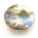 A silver pill box, the hinged lid decorated with a guilloche enamel landscape scene depicting figure