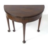 A mid 18thC mahogany demi lune card table with a double hinged top, the first section lifting to
