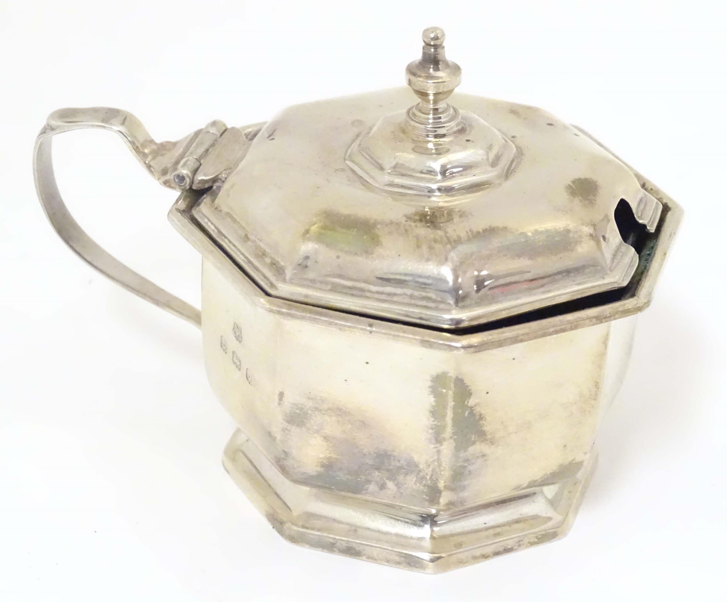 A silver mustard pot of octagonal form with blue glass liner. Hallmarked Birmingham 1933, maker