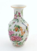 A small Chinese famille rose baluster vase decorated with butterflies amongst flowers and foliage.