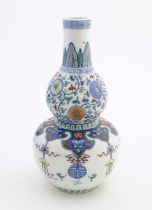 A Chinese double gourd vase with doucai style decoration with scrolling floral and foliate detail.