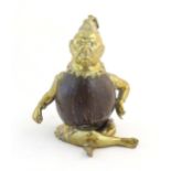 An early 20thC novelty brass and coconut inkwell modelled as a seated man wearing a plume hat.