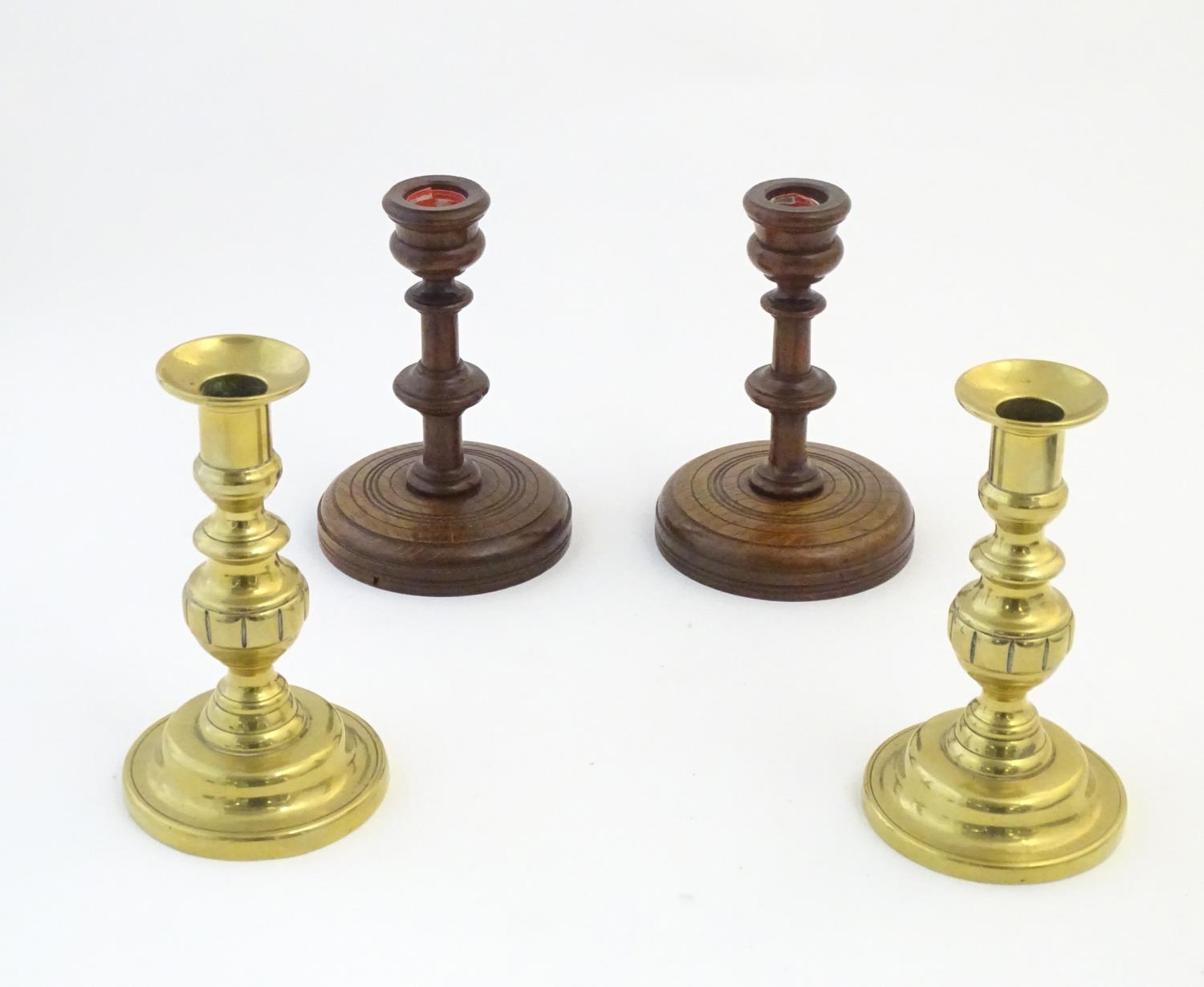 A pair of brass candlesticks with plunger action. Together with a pair of turned oak candlesticks.