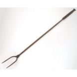 A large wrought iron fireside log fork, the flat handle decorated with opposing scrolls, approx 46