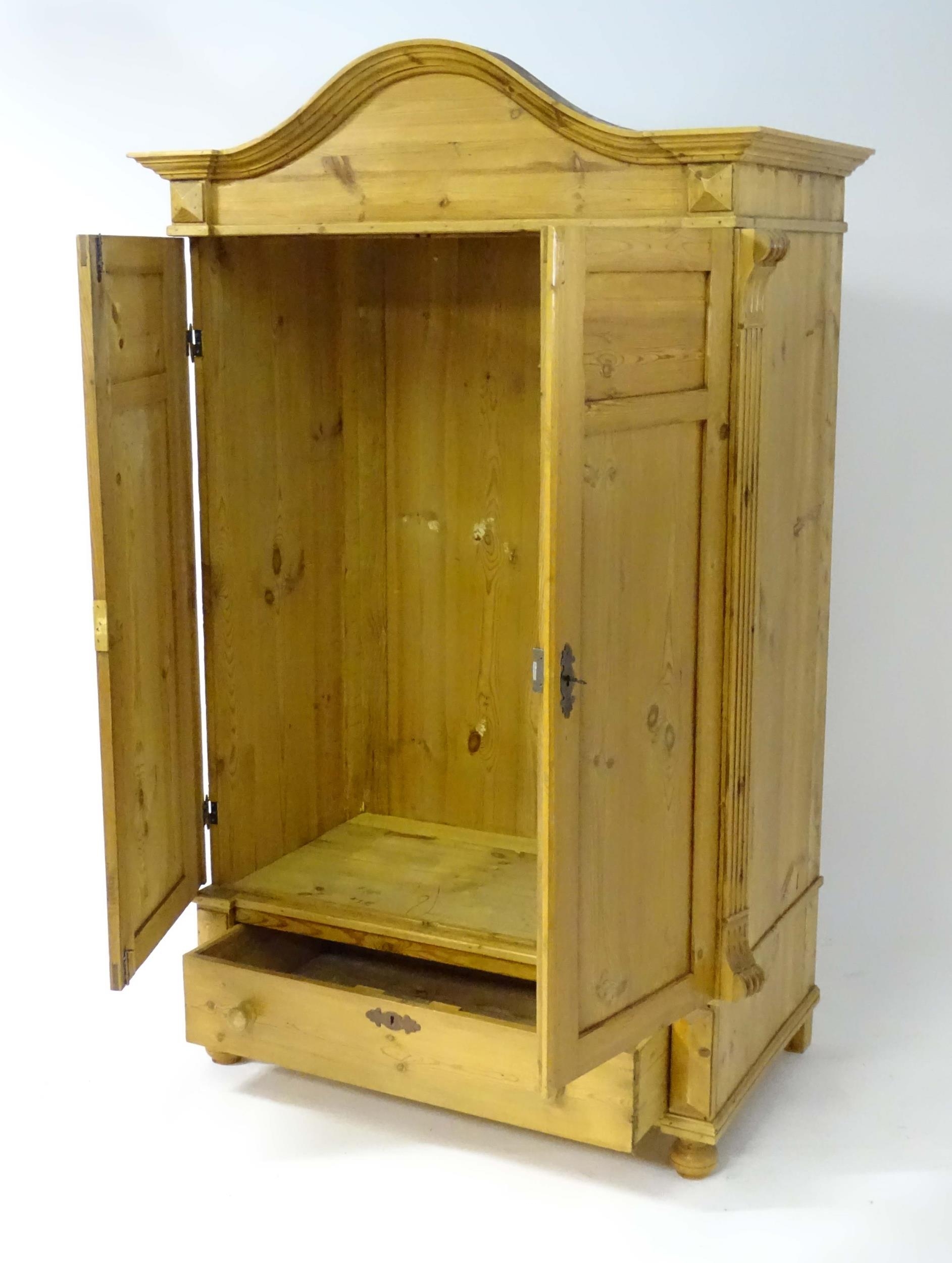 A 20thC continental pine wardrobe with an arched cornice above two panelled doors flanked by - Bild 4 aus 4