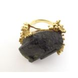 An unusual 18ct gold ring set with black jet coloured hardstone specimen with textured shoulders.