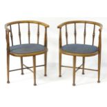 A pair of Arts & Crafts tub chairs with curved back rests above spindle turned supports and raised