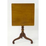 A late Georgian mahogany tilt top table with a square top above a pedestal base and three scrolled
