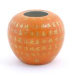 A small Chinese vase of squat form with an orange ground and gilt character script decoration to