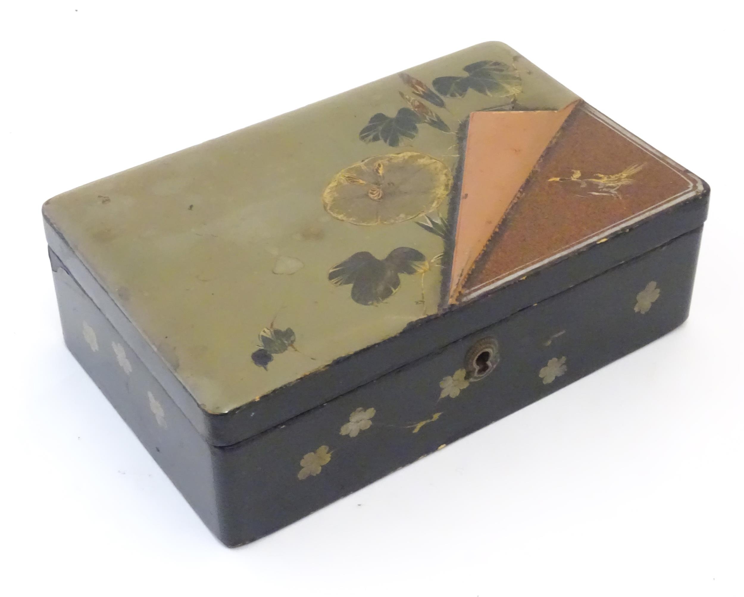 A Japanese lacquered box with hinge lid decorated with flowers and foliage, with faux lifted