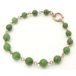 A bracelet of green jade beads with yellow metal links and clasp. Approx. 7 1/2" long Please