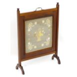 An early 20thC mahogany fire screen with a carrying handle to the top above a needlework centre. 24"