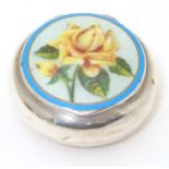 A silver pill box of circular form with enamel floral detail to lid. Marked with importers mark