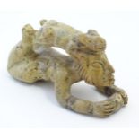 A 20thC soapstone model of a stylised figure lying on their front with a stylised rabbit / animal on