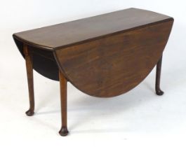 A Georgian mahogany drop leaf table raised on straight legs terminating in pad feet. 54" wide x