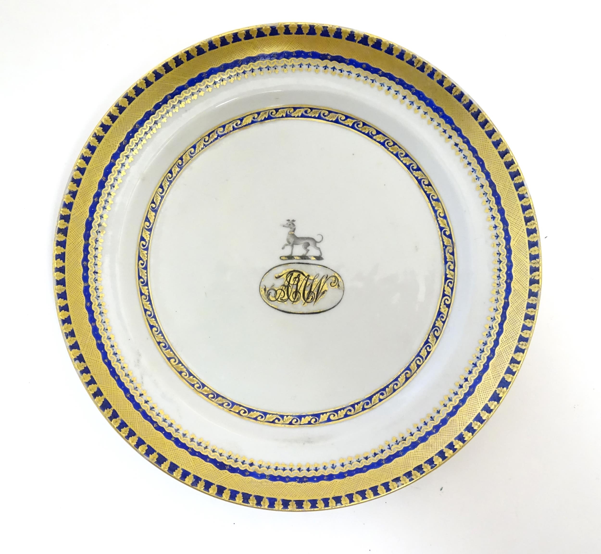 A Chinese Export plate with long dog armorial and monogram under, with gilt leaf border. Approx. 7