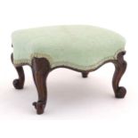 A 19thC rosewood footstool with serpentine shaped sides and an upholstered top above cabriole legs