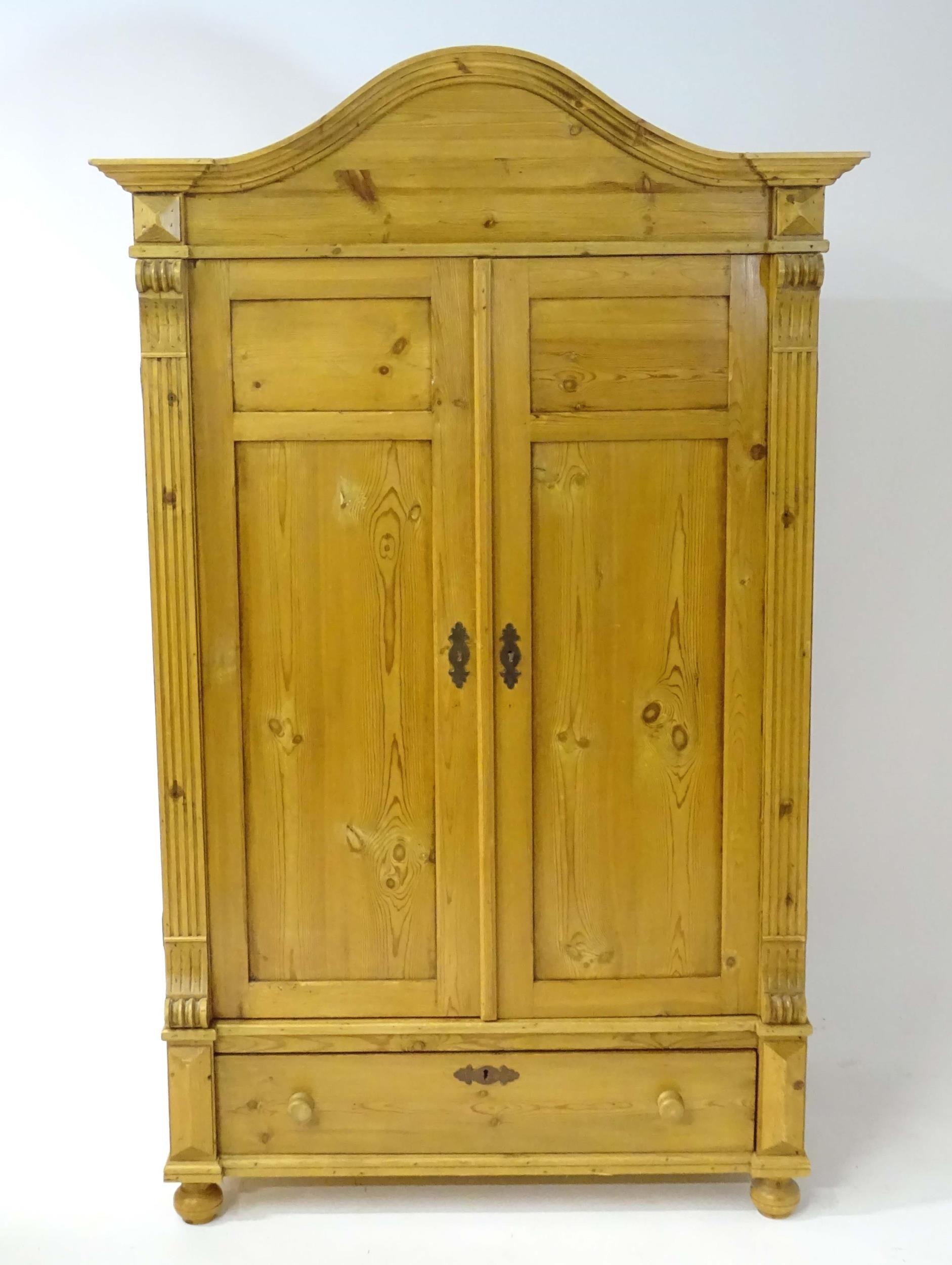A 20thC continental pine wardrobe with an arched cornice above two panelled doors flanked by - Bild 3 aus 4