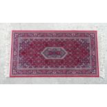Carpet / Rug : A red ground rug with central blue ground motif and cream borders decorated with