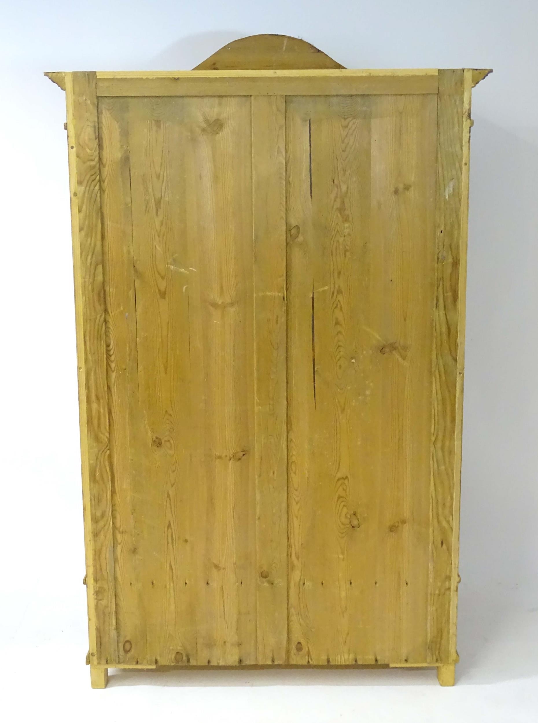 A 20thC continental pine wardrobe with an arched cornice above two panelled doors flanked by - Bild 2 aus 4