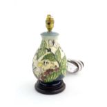 A Moorcroft table lamp base decorated in the Strawberry Plant and Butterfly pattern, on a turned